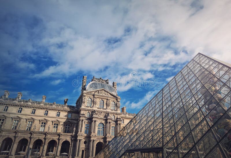 Utomhusvy till det högre museet i paris france. Den historiska palatesbyggnaden med den moderna glaspyramiden i centrum