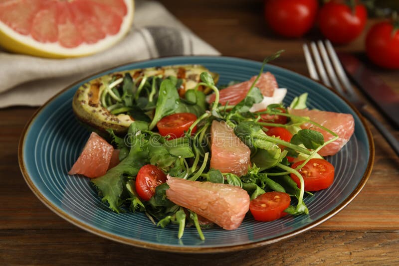 Utsökt pomelosallad med grillad avokado serverad på träbordsduk arkivfoto
