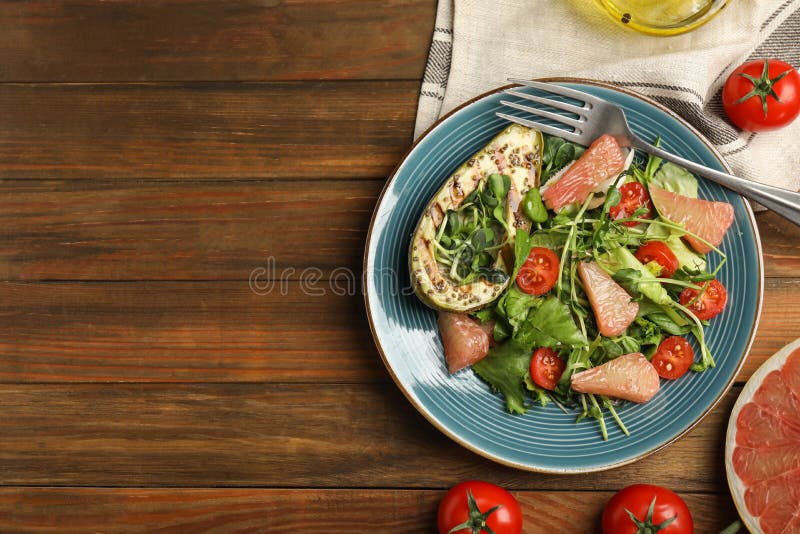 Utsökt pomelosallad med grillad avokado som serveras på plattlägg av trä. utrymme för text royaltyfri foto