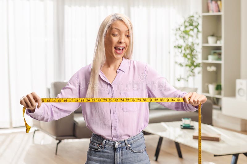 Utsökt ung kvinna som tittar på ett måttband arkivbild