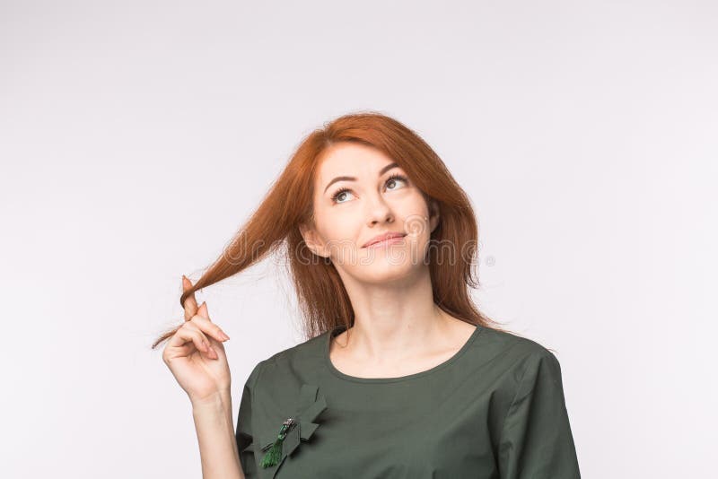 Uttrycks- och folkbegrepp - stående av en härlig ung kvinna med rött hår som tänker över vit bakgrund fotografering för bildbyråer Uttrycks- och folkbegrepp - stående av en härlig ung kvinna med rött hår som tänker över vit bakgrund fotografering för bildbyråer