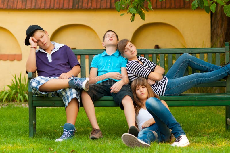 Bored teenagers sitting and lying on the bench on beautiful spring day. Bored teenagers sitting and lying on the bench on beautiful spring day.