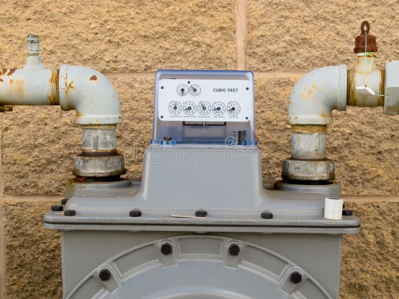 Residential natural gas meter on exterior wall to measure household energy consumption shows reading on dial display. Residential natural gas meter on exterior wall to measure household energy consumption shows reading on dial display