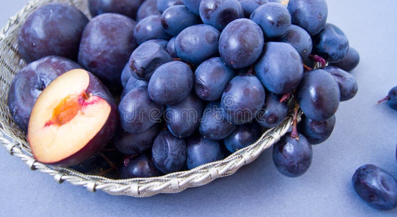 Uva e prugne in una ciotola d'argento immagini stock Uva e prugne in una ciotola d'argento immagini stock
