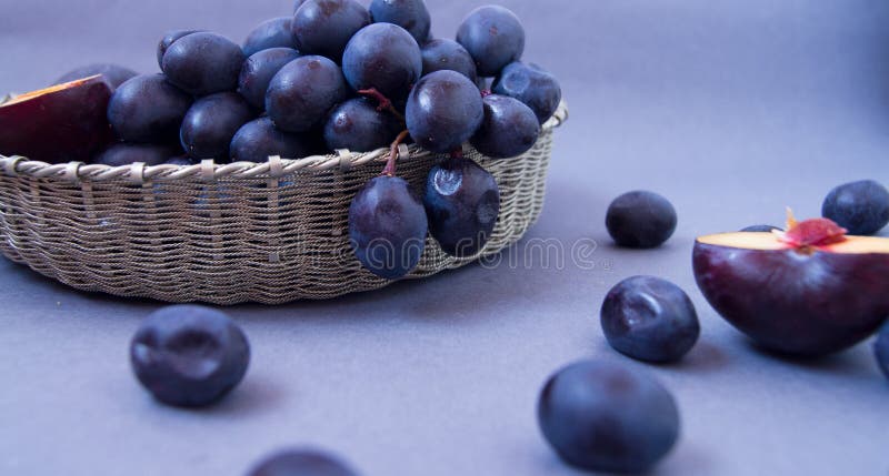 Uvas e ameixas em uma bacia de prata em um fundo escuro fotos de stock royalty free Uvas e ameixas em uma bacia de prata em um fundo escuro fotos de stock royalty free