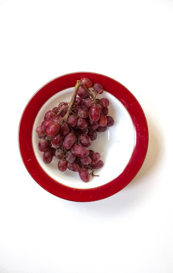 Uvas vermelhas em uma bacia branca vermelho-orlarada imagem de stock Uvas vermelhas em uma bacia branca vermelho-orlarada imagem de stock