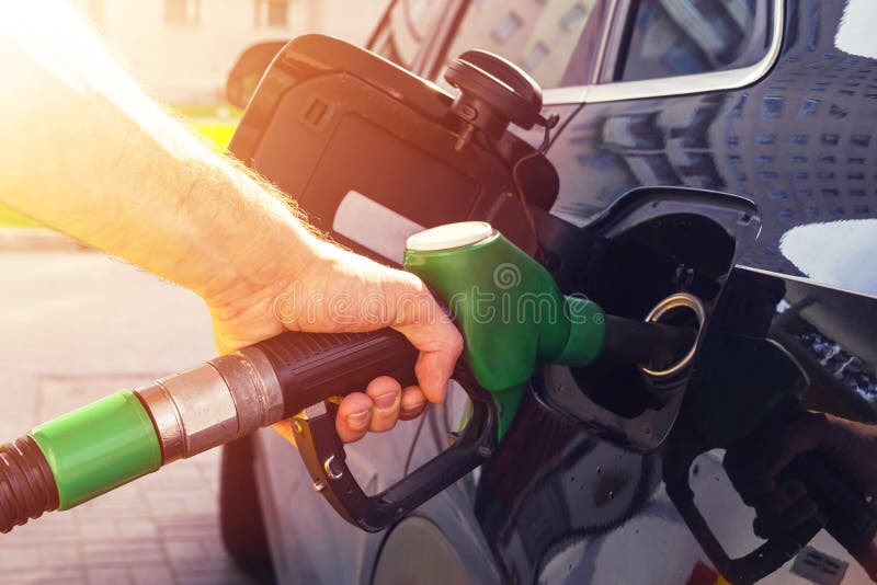 Uzupełnienie samochód przy benzynowej staci paliwową pompą Mężczyzny kierowcy ręka refilling benzynę i pompuje oliwi samochód z p