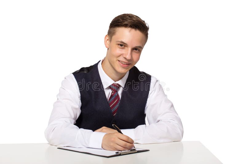 Uśmiechnięty młody biznesmen pracuje w biurze, siedzący przy biurkiem, pisze notatkach schowek obrazy royalty free Uśmiechnięty młody biznesmen pracuje w biurze, siedzący przy biurkiem, pisze notatkach schowek obrazy royalty free