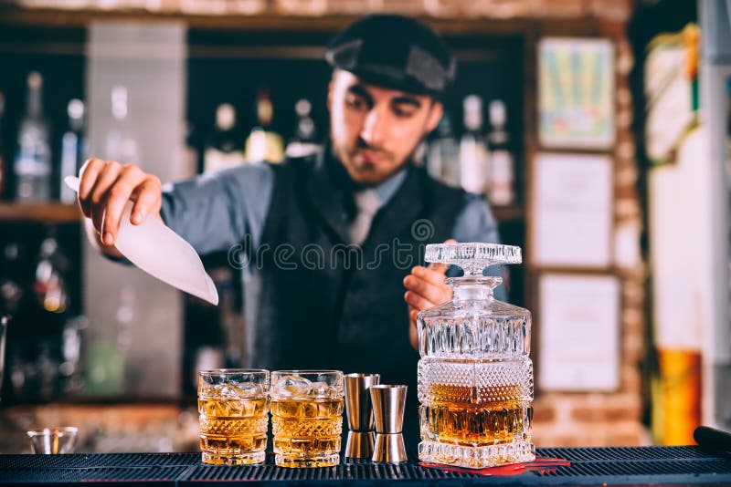 uísque de derramamento e gelo do barman elegante em cocktail frescos na barra moderna imagens de stock royalty free uísque de derramamento e gelo do barman elegante em cocktail frescos na barra moderna imagens de stock royalty free