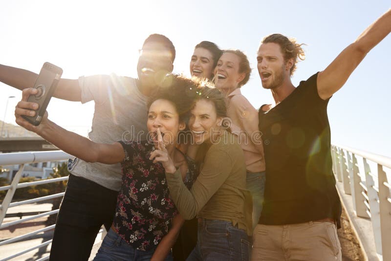 Uśmiechnięci Młodzi przyjaciele Pozuje Dla Selfie Na Plenerowym Footbridge Wpólnie fotografia stock Uśmiechnięci Młodzi przyjaciele Pozuje Dla Selfie Na Plenerowym Footbridge Wpólnie fotografia stock