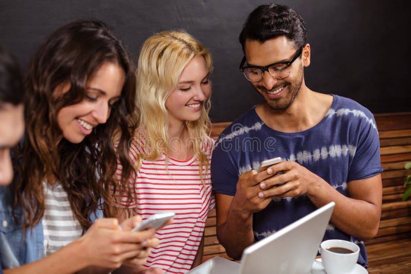 Uśmiechnięci przyjaciele ogląda smartphone wpólnie przy sklep z kawą