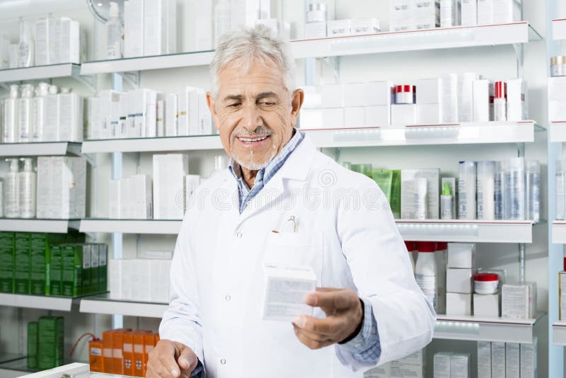 Uśmiechnięta chemika mienia medycyna Przy kontuarem W aptece zdjęcie stock Uśmiechnięta chemika mienia medycyna Przy kontuarem W aptece zdjęcie stock