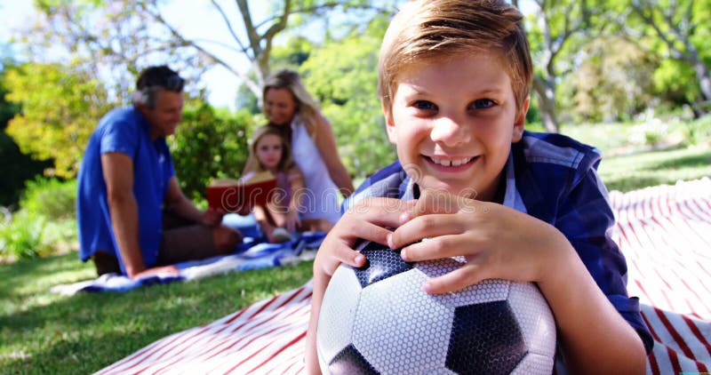 Uśmiechnięta chłopiec opiera na jego futbolu w pinkinie przy parkiem 4k