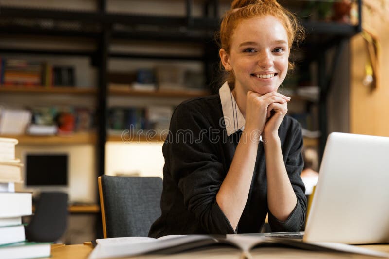 Uśmiechnięta czerwona z włosami nastoletnia dziewczyna używa laptop zdjęcie royalty free Uśmiechnięta czerwona z włosami nastoletnia dziewczyna używa laptop zdjęcie royalty free
