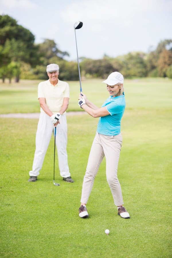 Uśmiechnięta golfista kobieta bierze strzał fotografia stock Uśmiechnięta golfista kobieta bierze strzał fotografia stock