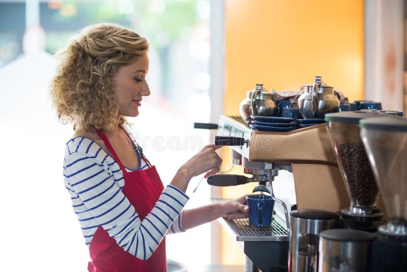 Uśmiechnięta kelnerka robi filiżance kawy zdjęcie stock Uśmiechnięta kelnerka robi filiżance kawy zdjęcie stock