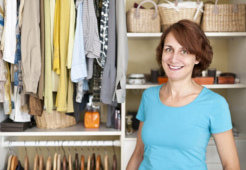 Happy woman standing in front of custom organized closet at home. Happy woman standing in front of custom organized closet at home