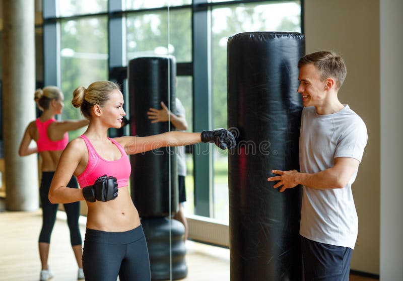 Uśmiechnięta kobieta z osobistym trenera boksem w gym
