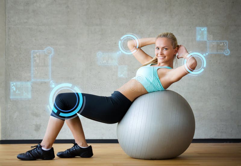 Fitness, sport, training, future technology and lifestyle concept - smiling woman with exercise ball in gym over virtual screen projections. Fitness, sport, training, future technology and lifestyle concept - smiling woman with exercise ball in gym over virtual screen projections.
