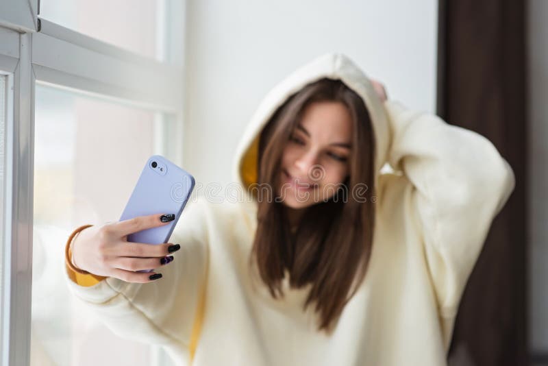 Uśmiechnięta młoda nastolatka telewizja z telefonem komórkowym, rozmawiająca z rodziną przyjaciół, zabierająca selfie dla mediów s zdjęcie royalty free