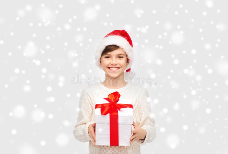 Uśmiechnięta szczęśliwa chłopiec w Santa kapeluszu z prezenta pudełkiem zdjęcie royalty free Uśmiechnięta szczęśliwa chłopiec w Santa kapeluszu z prezenta pudełkiem zdjęcie royalty free