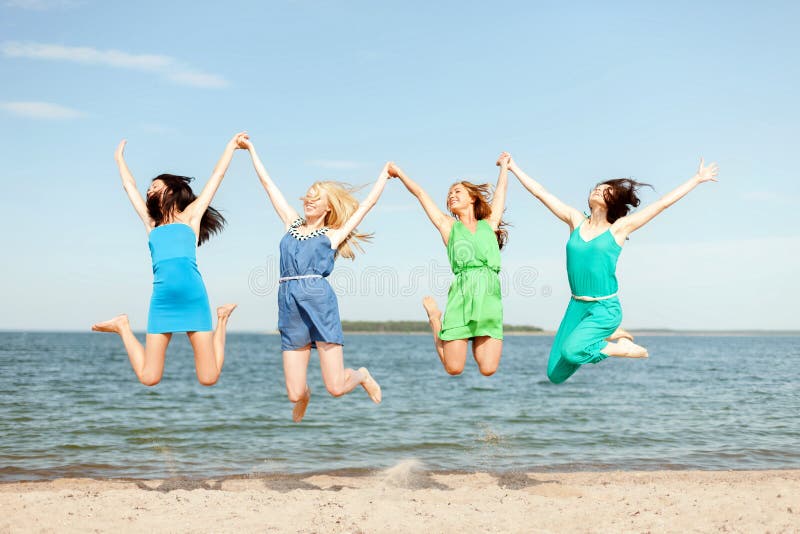 Summer holidays and vacation concept - smiling girls jumping on the beach. Summer holidays and vacation concept - smiling girls jumping on the beach