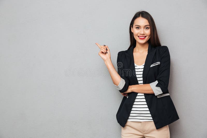 Uśmiechnięty azjatykci biznesowej kobiety wskazywać up i patrzeć kamerę