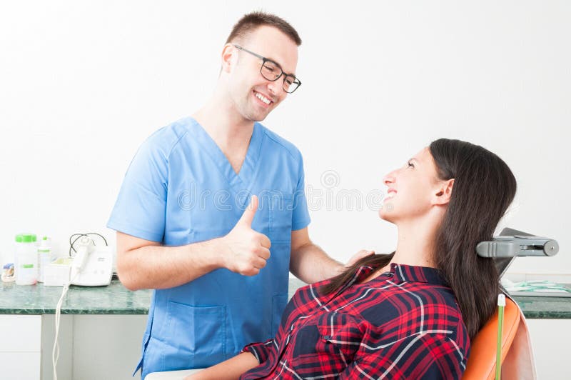 Uśmiechnięty dentysta pokazuje kciuk do jego pacjenta fotografia stock Uśmiechnięty dentysta pokazuje kciuk do jego pacjenta fotografia stock
