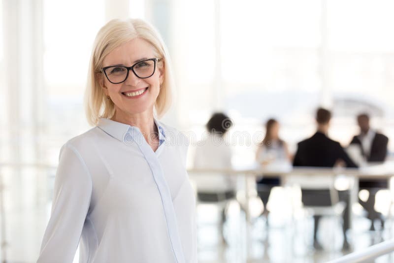 Uśmiechnięty dojrzały atrakcyjny bizneswoman patrzeje w ca w szkłach obraz stock Uśmiechnięty dojrzały atrakcyjny bizneswoman patrzeje w ca w szkłach obraz stock