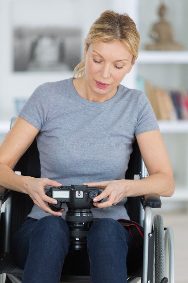 Uśmiechnięty żeński fotograf na wózku inwalidzkim zdjęcie stock Uśmiechnięty żeński fotograf na wózku inwalidzkim zdjęcie stock