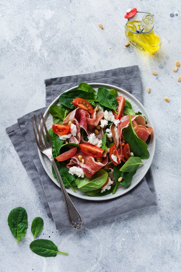 V?rsallad med spenat, den k?rsb?rsr?da tomaten, mozzarella, s?rjer muttrar och skinka med olivolja i en enkel keramisk platta fotografering för bildbyråer V?rsallad med spenat, den k?rsb?rsr?da tomaten, mozzarella, s?rjer muttrar och skinka med olivolja i en enkel keramisk platta fotografering för bildbyråer