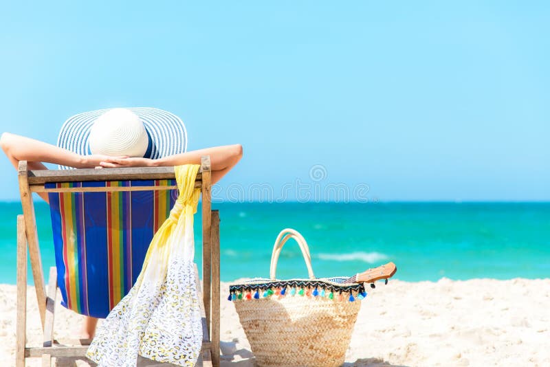 Vacaciones de verano Mujer sana de la forma de vida asiática relajante y feliz en silla de playa con el jugo del coco del cóctel