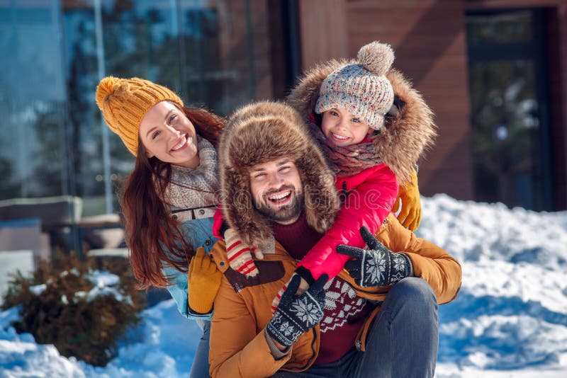 Vacaciones del invierno Tiempo de la familia junto al aire libre que se sienta abrazando el primer dentudo sonriente foto de archivo Vacaciones del invierno Tiempo de la familia junto al aire libre que se sienta abrazando el primer dentudo sonriente foto de archivo