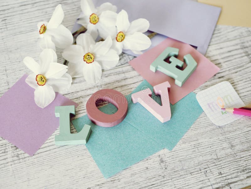 Vacances du jour de mère, composition de l'amour de mot des lettres en vrac, fleurs fraîches, enveloppe, papier, crayons sur la t photo libre de droits Vacances du jour de mère, composition de l'amour de mot des lettres en vrac, fleurs fraîches, enveloppe, papier, crayons sur la t photo libre de droits