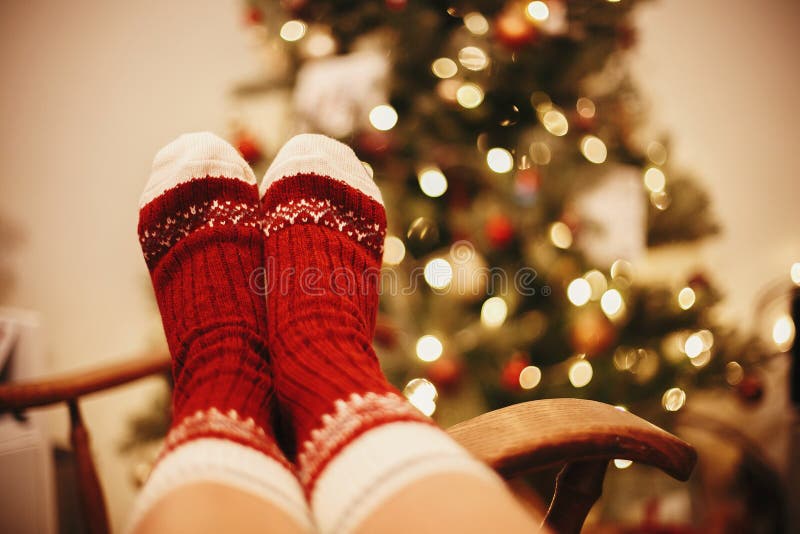 Cozy winter holidays. warm atmospheric moment. festive socks on old wooden chair on background of golden beautiful christmas tree with lights in festive room. relax time. Cozy winter holidays. warm atmospheric moment. festive socks on old wooden chair on background of golden beautiful christmas tree with lights in festive room. relax time