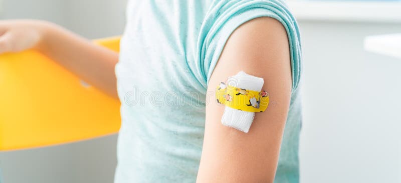Vaccination of little girl in doctor`s office.Kids funny adhesive plaster,gauze napkin.Sits on chair.Vaccine for covid-19 royalty free stock image Vaccination of little girl in doctor`s office.Kids funny adhesive plaster,gauze napkin.Sits on chair.Vaccine for covid-19 royalty free stock image