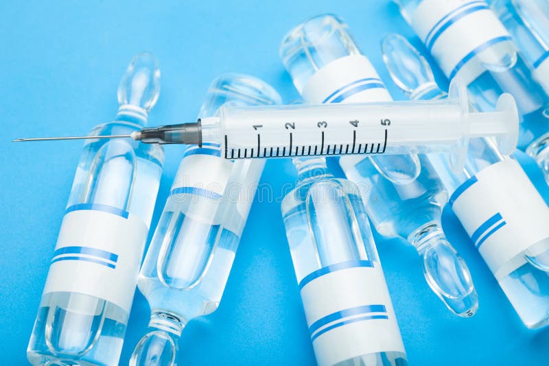 Vaccinflesjes met spuit op blauwe achtergrond stock fotografie Vaccinflesjes met spuit op blauwe achtergrond stock fotografie