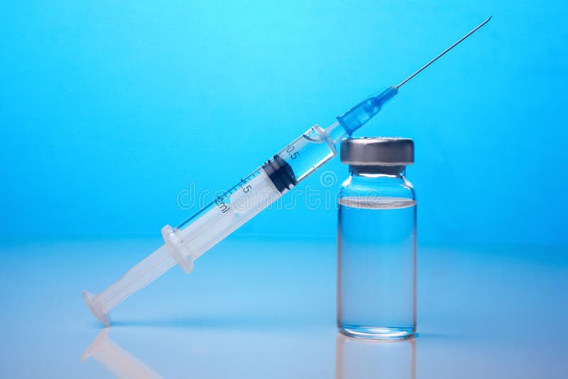 Vacinas e seringa da agulha da droga da vacina contra a gripe no fundo azul fotos de stock Vacinas e seringa da agulha da droga da vacina contra a gripe no fundo azul fotos de stock