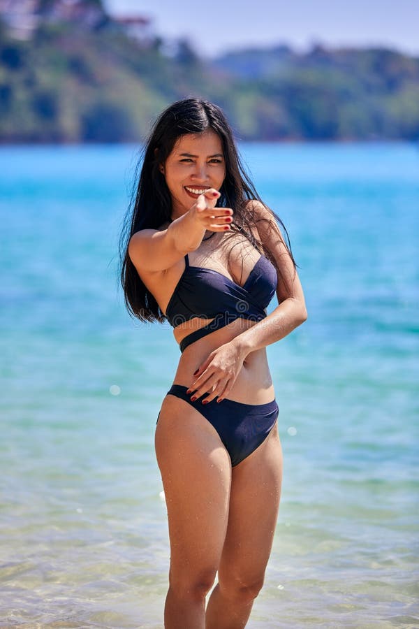 Vacker asiatisk kvinna som pockar på en tropisk strand