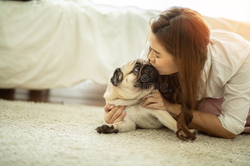 Vacker, attraktiv, asiatisk kvinna som kysser sin söta hundpug ras royaltyfri foto