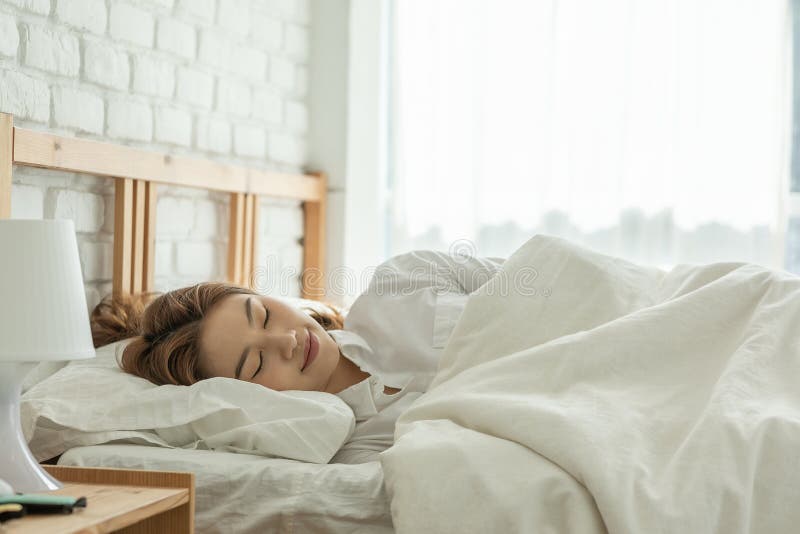 Vacker, attraktiv, asiatisk kvinna sover och söt dröm om sängen i sovrummet arkivbilder