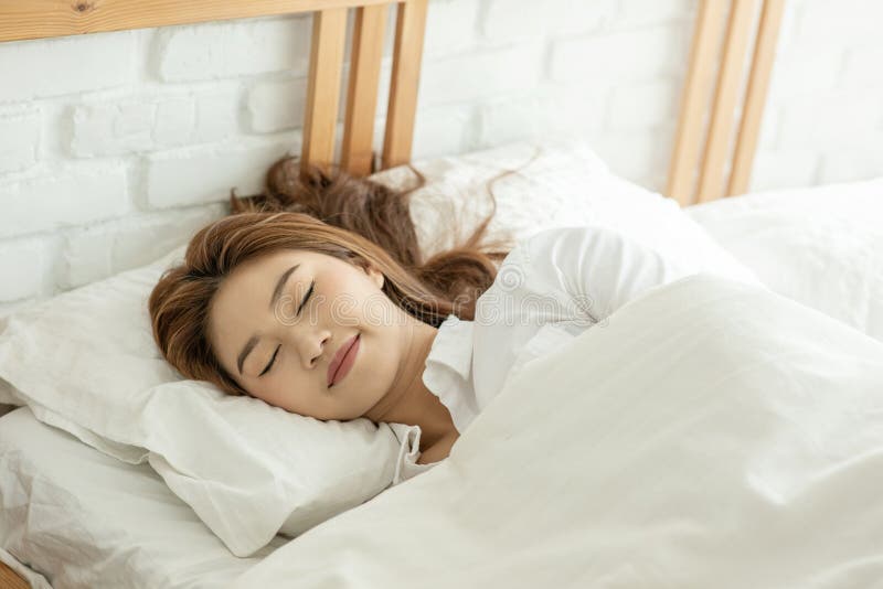 Vacker, attraktiv, asiatisk kvinna sover och söt dröm om sängen i sovrummet royaltyfri bild