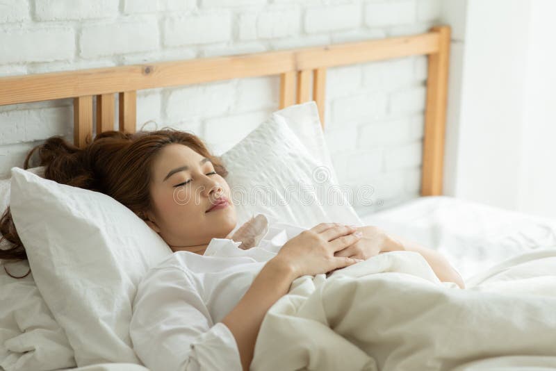 Vacker, attraktiv, asiatisk kvinna sover och söt dröm om sängen i sovrummet fotografering för bildbyråer
