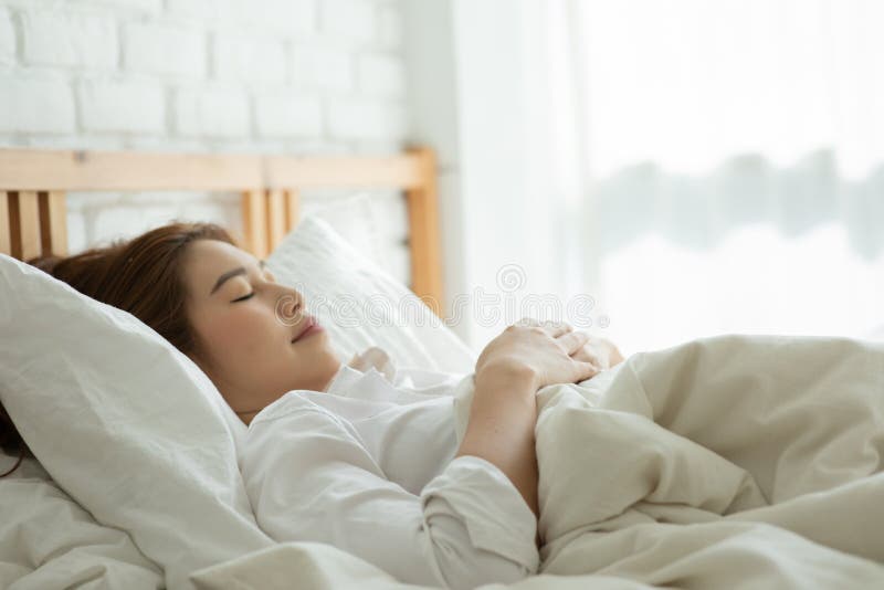 Vacker, attraktiv, asiatisk kvinna sover och söt dröm om sängen i sovrummet arkivfoto