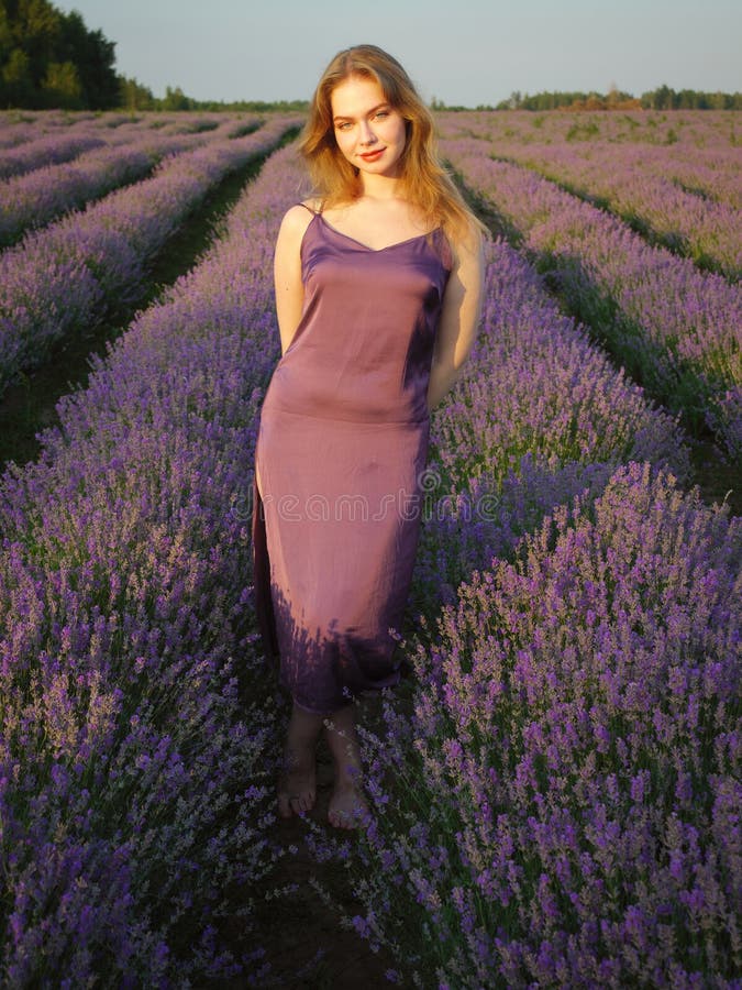 Vacker blond flicka med långt hår på ett lavenderfält på kvällen royaltyfri fotografi
