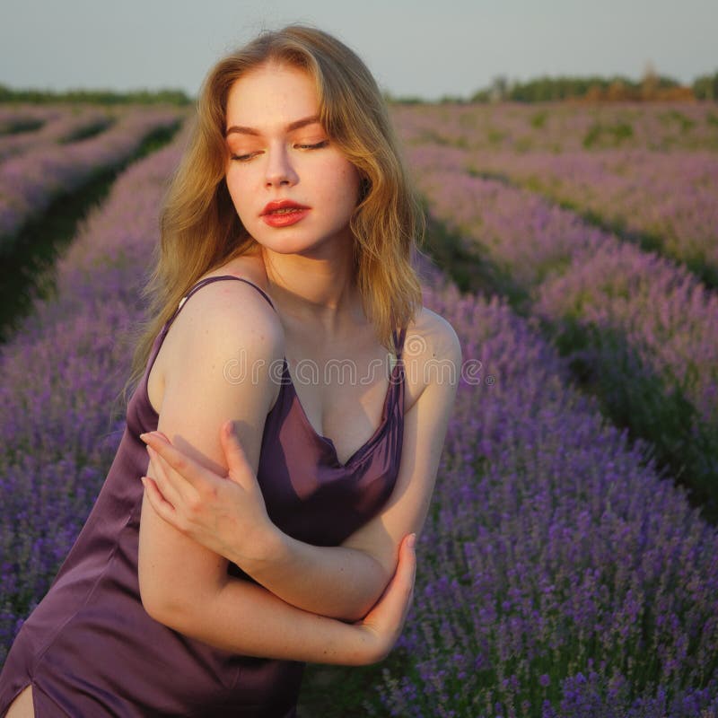Vacker blond flicka med långt hår på ett lavenderfält på kvällen fotografering för bildbyråer