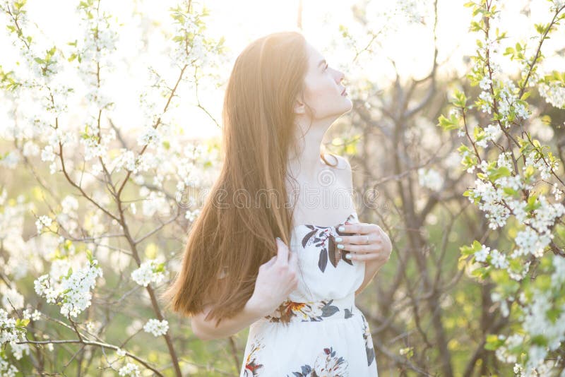 Vacker flicka bland körsbärsblommor på en solig vårdag fotografering för bildbyråer