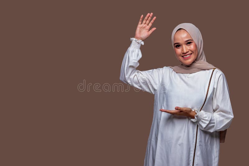 Vacker hijabisk kvinna som visar den nuvarande gesthanden isolerad på ren bakgrund.
