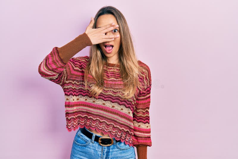 Vacker historisk kvinna som bär hippie sweater och som pissar i ett chocktäcke av ansikte och ögon med handen som ser genom fingra arkivbilder