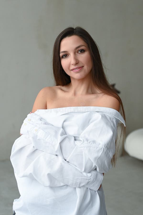 Vacker kvinna i vit skjorta med benskulor. ung, vacker brunette-kvinna minimalistisk porträtt. lodrät royaltyfri foto